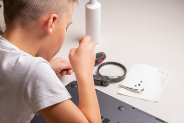 A boy of 10 years old is sorting a laptop for cleaning and maintenance. Selective focus....