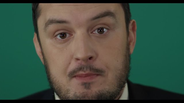 Close-up of young man dubious swindler talking foolish things on camera trying to deceive people. Political lier. Shot with green screen background