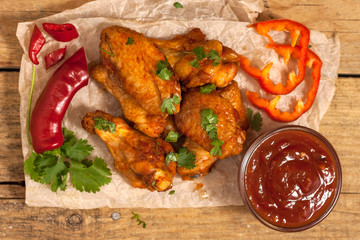 Fried juicy chicken wings marinated with honey, soy sauce, spices, sprinkled with finely chopped cilantro on a paper background. Asian recipe, top view, close-up.