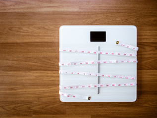 weight loss and physical activity concept from weight scale digital with measure tape for check body shape on wooden floor.