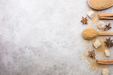Christmas background with cinnamon sticks,anise stars and brown cane sugar in wooden spoon on grey background.Top view.