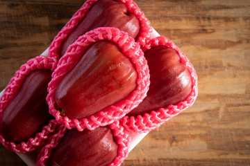 Rose apples in foam tray on wooden background.