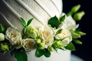 Cake is decorated with flowers on a dark background.