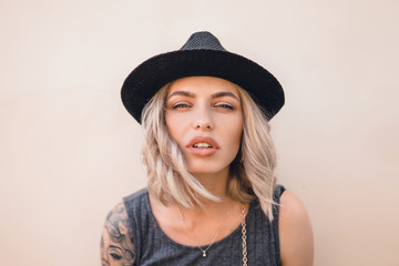 emotional portrait of Fashion stylish portrait of pretty young hipster blonde woman,going crazy,elegant black hat,soft colors,cool crazy  girl.Red urban wall background.surprised girl close up, sunset