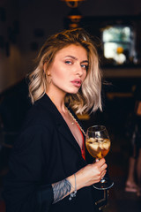 Beautiful girl in drinks Aperol Spritz wine from a glass in a restaurant, a cafe, has a good weekend, a stylish fashionable woman, a brunette young, emotional, outdoor close up hipster portrait