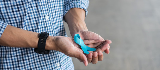 November Prostate Cancer Awareness month, Man in blue shirt with hand holding Blue Ribbon for...