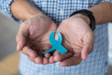 November Prostate Cancer Awareness month, Man in blue shirt with hand holding Blue Ribbon for...
