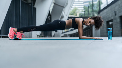 Woman in sportswear doing planks exercising outdoors