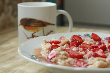 Homemade oatmeal with strawberries and a cup of milk.
