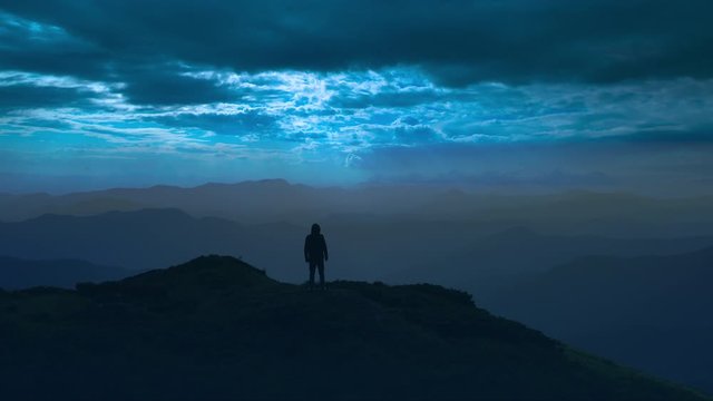 The man standing on a mountain top on the moolight background