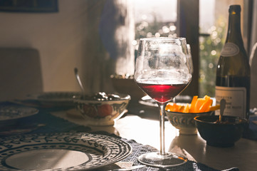 Glass of wine on the dining table. Sun glare. Toned photo.