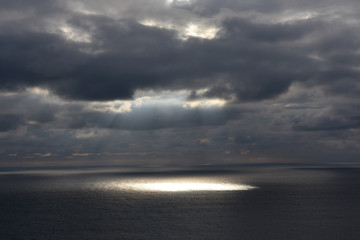 a sunbeam that sneaks through the clouds and goes to the sea in Cabo Raso, Portugal