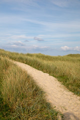Sandweg durch die Dünen mit blauem Himmel und Strandgras