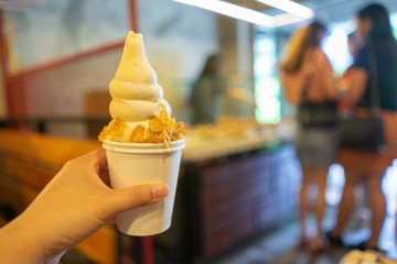 Hand holding milk soft serve ice cream. Food background.