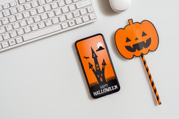 Happy Halloween Mobile phone mockup background concept. Top view of smartphone on office desk table with accessories. Flat lay design. Business and technology Halloween day concepts ideas.