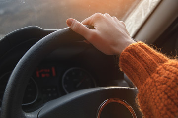 Close-up of a female hand in an orange sweater driving a car outside the city. Slow motion Woman...