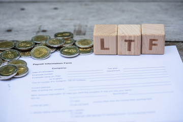 Word block LTF on payroll information form, and pile of coins. Income, expenses, tax, tax deduction, and financial data.