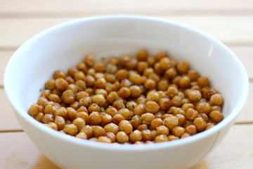 Bowl of roasted crispy chickpeas on wooden table. Selective focus.