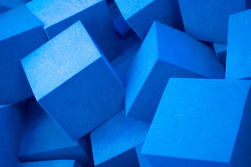 Randomly lying blue foam cubes. Graphic concept. Blue foam cut into cubes. Blue background. Volumetric image. Styrofoam