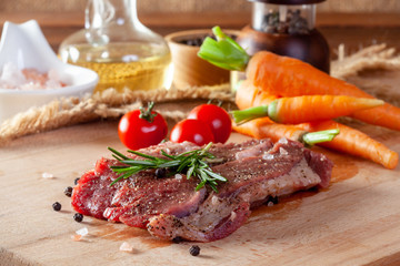 Beef steak with vegetables and spices on a cutting board