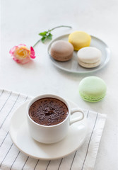 cup of hot chocolate with macarons flowers on a white background