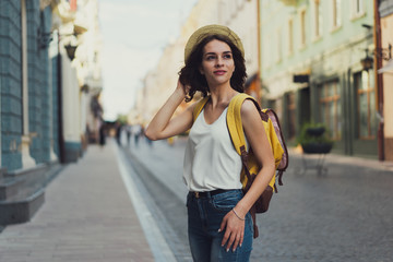 Obraz premium Smiling woman traveler with a backpack. On the street of an old town. With a beautiful architecture on the background.