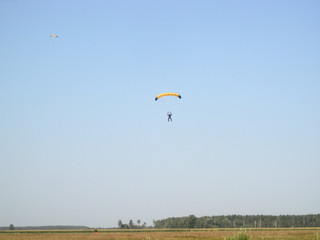 A paratrooper in the distance against the sky is approaching the ground