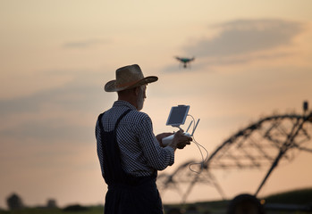 Farmer with drone in field with irrigation system