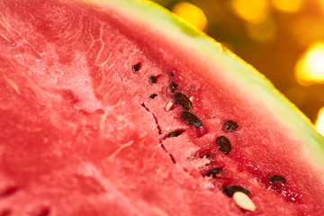 Fresh ripe striped sliced watermelon on wooden table with blurred garden sunset background. Food, Fruits or healthcare concept.