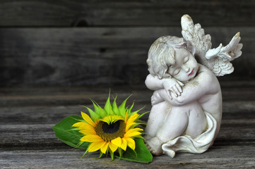 Guardian angel and sunflower on wooden background
