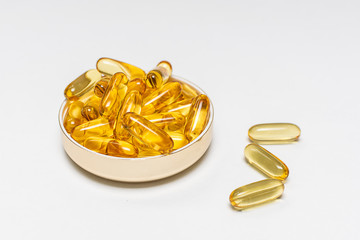 Cod liver oil capsules with omega 3 and vitamin E in a plate isolated on white background, copy...