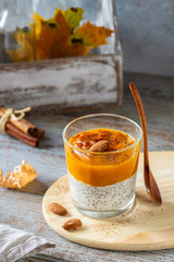 Healthy breakfast - Chia seeds pudding with spicy pumpkin puree and almonds on gray wooden rustic table. Health care, fitness, diet, super food concept.