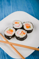 sushi roll lying on white plate. Blue background