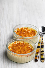 Closeup of creme brulee in glass jars on white wooden table