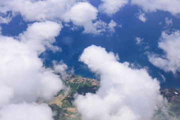 Beautiful view of the sea and the coast of the island of San Miguel from the porthole of the plane. White clouds over the atlantic ocean. Azores, Portugal.