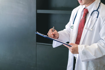 Male doctor writing on clipboard in the office.
