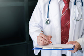 Male doctor writing on clipboard in the office.