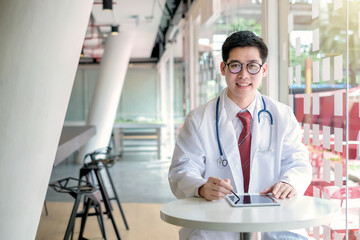 Male doctor asian using tablet and looking at camera in the office.