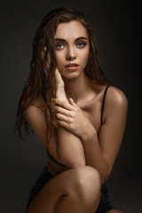 Fototapeta premium portrait of gorgeous sexy woman with perfect skin and long wet hair on dark background. girl looking at camera