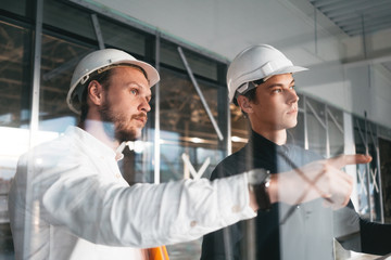 Building industry. Young engineer discussing with building worker on construction site. Industrial...