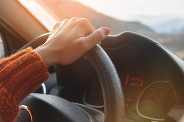 Close-up of a female hand in an orange sweater driving a car outside the city. Slow motion Woman...