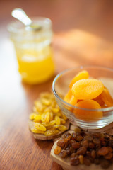 Raisins, dried apricots and honey on the table.