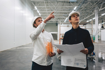 Building worker and architect discussing build drawing on construction site. Two industrial...