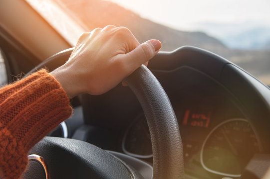Close-up of a female hand in an orange sweater driving a car outside the city. Slow motion Woman driving a car