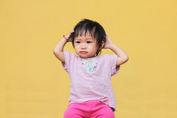 Soft focus. Portrait image of 1-2 years old of Asian baby child girl put her hand on her head and scratching hairs. She crying and sad. Expression and emotions of kid concept.