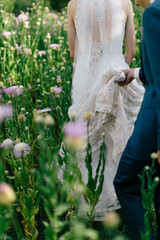 Groom holding brides dress, lace wedding dress train, summer wedding, wild flowers