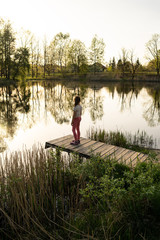 Fototapeta na wymiar Girl standing by the lake watching sunrise in Poland