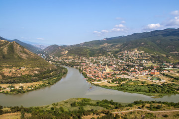 Confluence of the Mtkvari and Aragvi rivers viewed from above at Mtskheta - one of the oldest cities in Georgia - and view of the Svetitskhoveli Cathedral with mountains in background