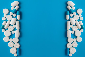 Scattered white pills on blue table. Mock up for special offers as advertising, web background or other ideas. Medical, pharmacy and healthcare concept. Copy space. Empty place for text or logo