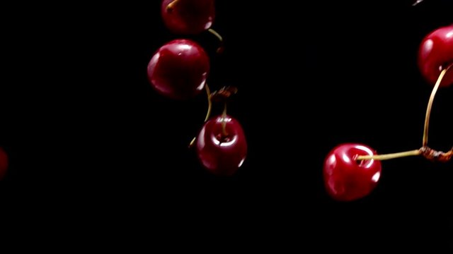 Rpe cherries fly on a black background closeup in slow motion